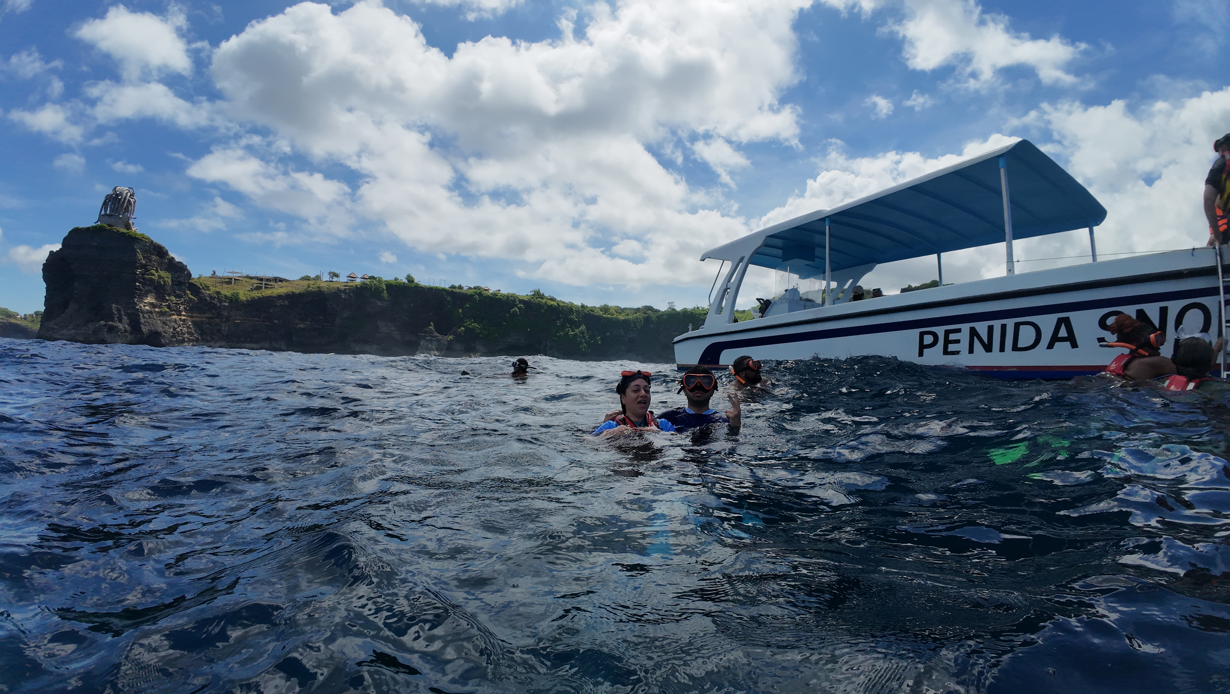 Snorkelling off Nusa Penida with dramatic cliff backdrop and boat