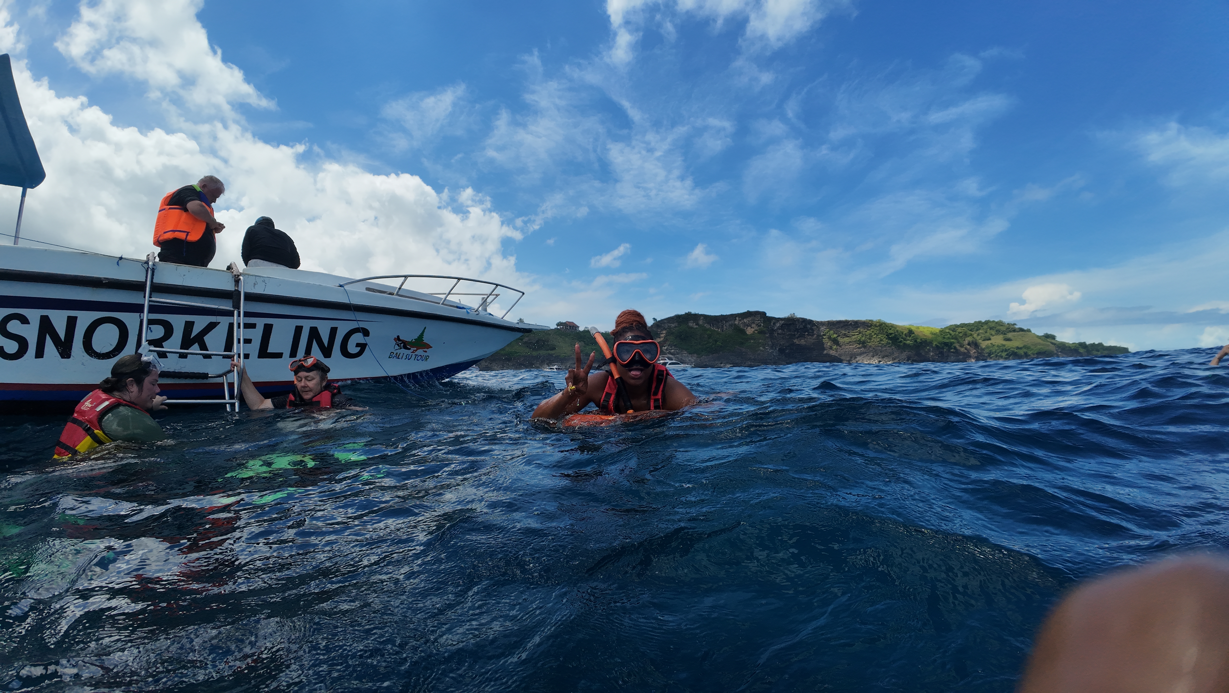 Snorkeller giving peace sign next to boat off Nusa Penida island